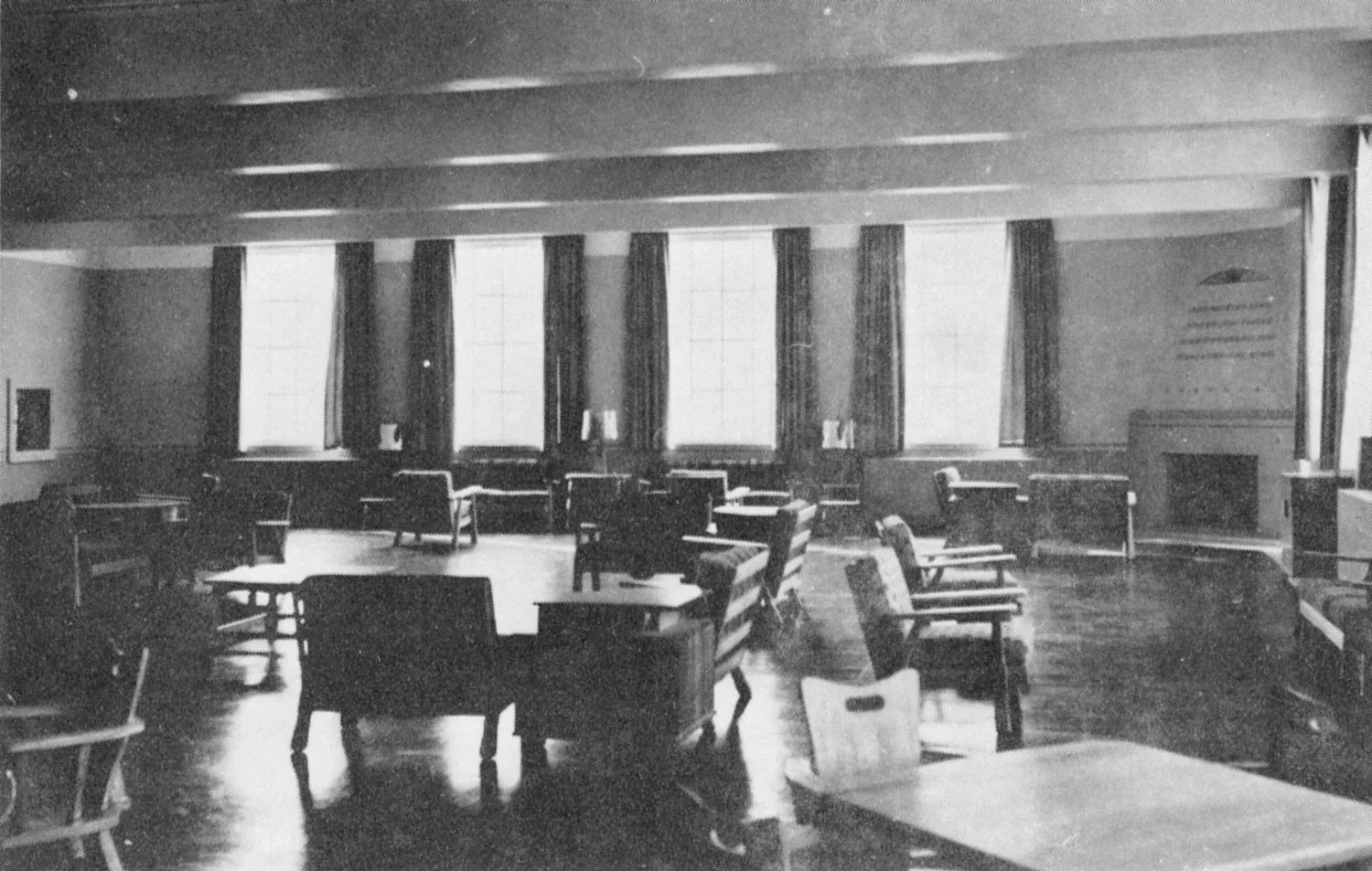 Tables and chairs in a public room with a fireplace and tall windows